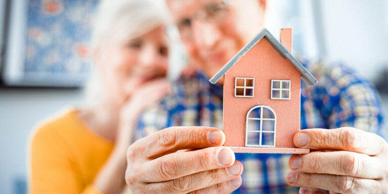 Senior Couple Holding House Model in Small Assisted Living Facility